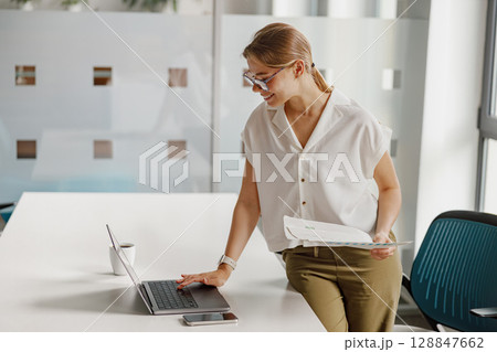 The dedicated businesswoman is diligently working on her laptop in a modern office space 128847662