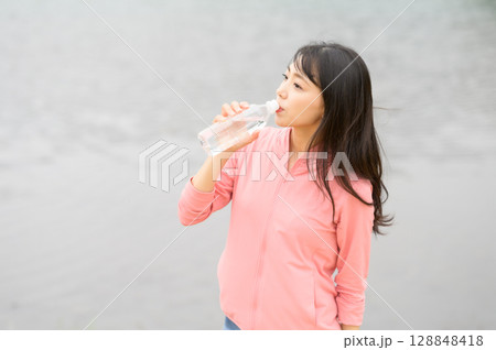 水辺でペットボトルを手に持つ女性 128848418