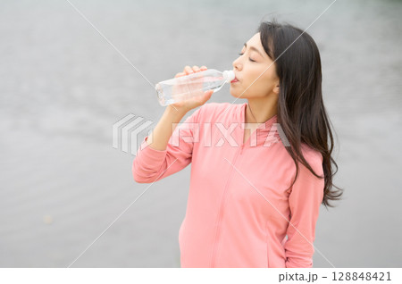 水辺でペットボトルを手に持つ女性 128848421
