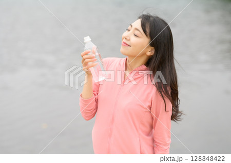 水辺でペットボトルを手に持つ女性 128848422