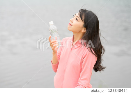 水辺でペットボトルを手に持つ女性 水辺でペットボトルを手に持つ女性 128848454