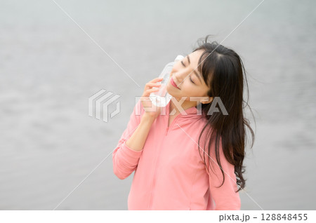 水辺でペットボトルを手に持つ女性 128848455