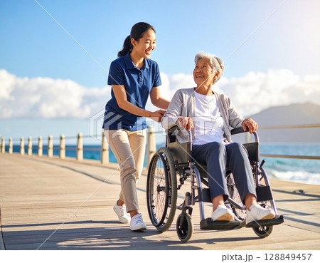 海岸を散歩する高齢者と介護士 海岸を散歩する高齢者と介護士 128849457