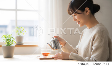リラックスタイムの女性、温かい飲み物と過ごす穏やかなひととき 128849654