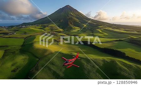 Red Plane Soaring Above Verdant Fields Near Pico Mountain, Azore 128850946