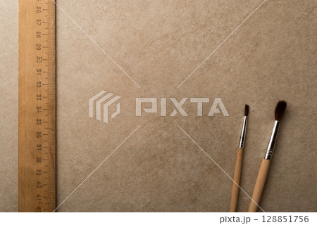 Wooden Ruler and Paintbrushes on Neutral Textured Background Surface 128851756