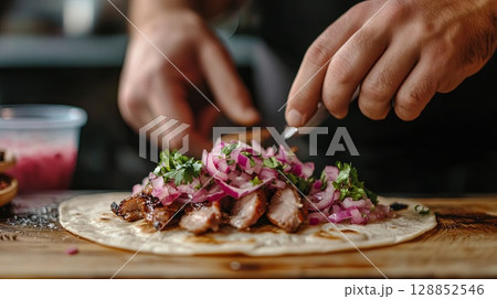 Gourmet tacos with roasted pork belly, pickled onions, and spicy salsa, served on a vintage wooden table . 128852546