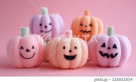 Cute wool felt pumpkins with smiling faces create playful Halloween scene on pink background 128852654