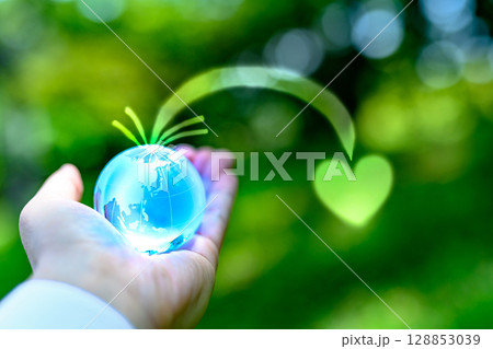 綺麗な新緑にかざす地球儀の水晶　地球から集まるハート　エコロジーイメージ　 128853039
