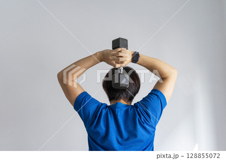 handsome man doing dumbbell workout at home, working on arms strength at living room interior. handsome man doing dumbbell workout at home, working on arms strength at living room interior. 128855072