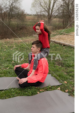 Kids enjoy playful yoga session in a serene outdoor setting while connecting with nature on a calm afternoon in the countryside 128856230