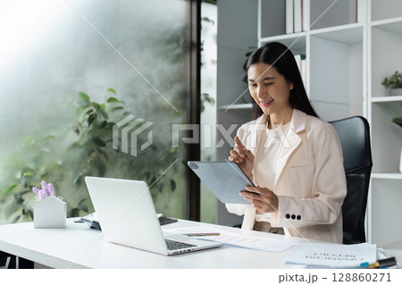 Professional Woman in Modern Office Using Tablet and Laptop for working in office 128860271