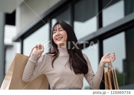 Joyful Woman Enjoying a Shopping Spree with Multiple Bags in a Modern Urban Setting Joyful Woman Enjoying a Shopping Spree with Multiple Bags in a Modern Urban Setting 128860738