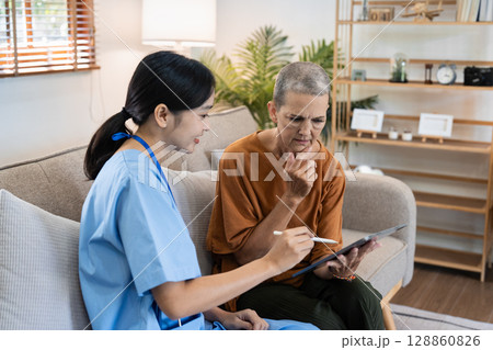 Healthcare Professional Conducting a Home Visit for Senior Woman, Providing Medical Consultation and Support in a Comfortable Living Room Setting 128860826
