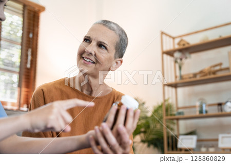 Senior Woman Receiving Healthcare at Home from a Caregiver, Discussing Medication and Treatment in a Comfortable Living Room 128860829