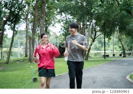 Young Couple Enjoying a Refreshing Jog in the Park During Their Morning Workout Routine 128860961