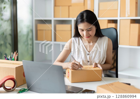 Young Entrepreneur Preparing Packages for Shipment in a Home Office for Online Small Business Young Entrepreneur Preparing Packages for Shipment in a Home Office for Online Small Business 128860994