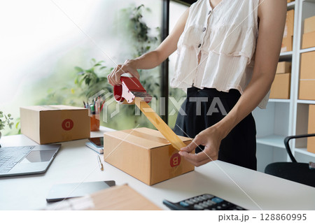 Small Business Owner Packing Order for Online Sales in a Modern Home Office 128860995