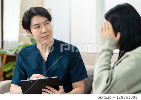 Healthcare Professional Conducting Home Visit Consultation with Patient in Comfortable Living Room Setting Healthcare Professional Conducting Home Visit Consultation with Patient in Comfortable Living Room Setting 128861008