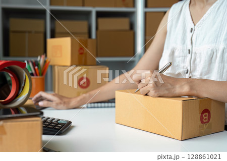 Entrepreneur Preparing Packages for Online Business Shipment in Home Office with Cardboard Boxes and Supplies 128861021