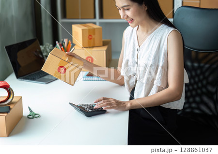 Young Entrepreneur Managing Online Business Orders and Finances in a Modern Home Office Setting 128861037