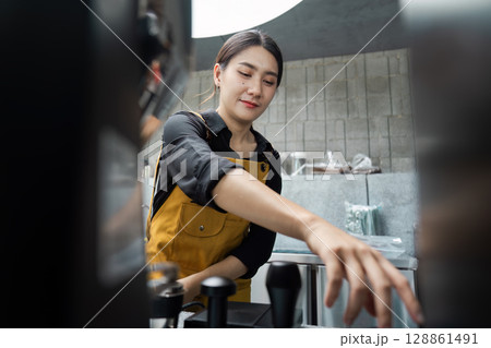 Young Female Barista Preparing Coffee in a Modern Cafe with Industrial Interior Design Young Female Barista Preparing Coffee in a Modern Cafe with Industrial Interior Design 128861491