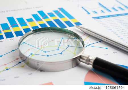 Magnifying glass on spreadsheet and graph paper. Financial data economy, Business. 128861804