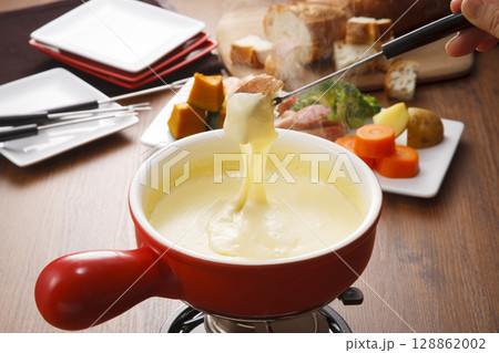 チーズフォンデュ　バゲットにチーズをつけている 128862002