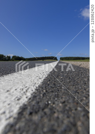paved road during the day in sunny weather , paved road for vehicles with white road markings paved road during the day in sunny weather , paved road for vehicles with white road markings 128862420