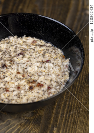 porridge with dried fruits in a black bowl , cooking instant oatmeal porridge, chia in porridge, top view porridge with dried fruits in a black bowl , cooking instant oatmeal porridge, chia in porridge, top view 128862434