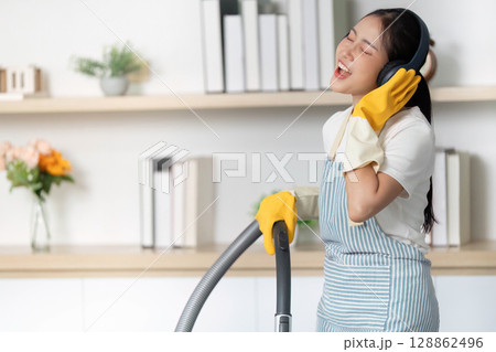 Home Cleaning. Woman enjoying music while vacuuming. Home Cleaning. Woman enjoying music while vacuuming. 128862496