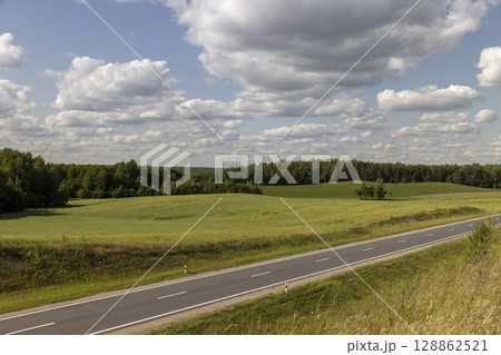 part of the paved road during the day in sunny weather , paved road for vehicles with white road markings 128862521