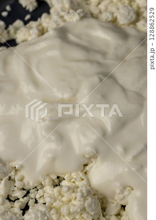 sprinkled with liquid sour cream, lumps of freshly made fermented milk product, closeup sprinkled with liquid sour cream, lumps of freshly made fermented milk product, closeup 128862529