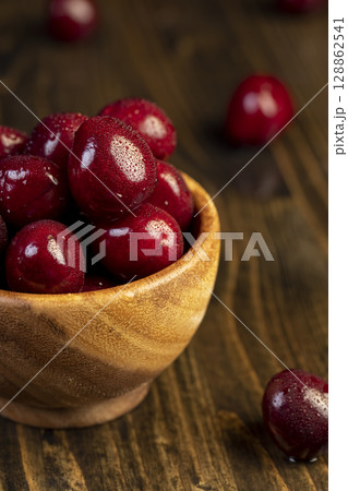 cherry berries in drops of water, wet red cherry fruits on the kitchen table closeup, berries in a wooden bowl , side view 128862541