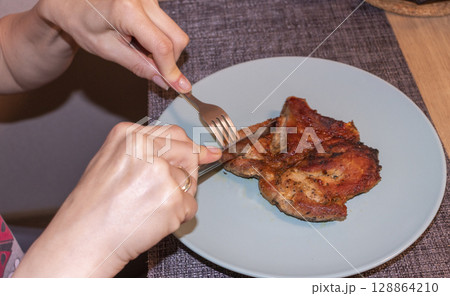 Woman cut of pieces of steak on ceramic plate Woman cut of pieces of steak on ceramic plate 128864210