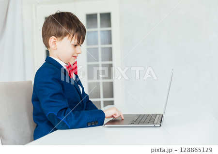 Schoolboy in Jacket Sitting At Table With Educational Laptop 128865129