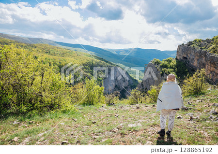 tourist looking at beautiful landscape on mountains, green forest and blue sky with clouds 128865192
