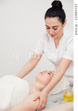 Massage therapist doing medical shoulder massage to woman 128865197
