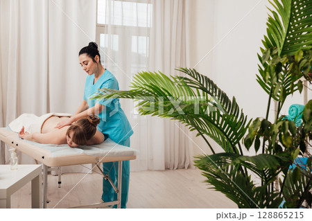Masseur doing hands medical back massage to woman 128865215