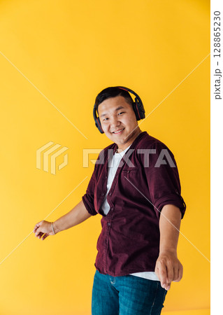 Asian man dancing to music in headphones Asian man dancing to music in headphones 128865230