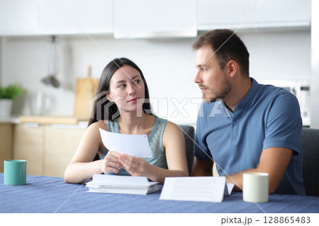 Serious interracial couple talking about bank statement Serious interracial couple talking about bank statement 128865483