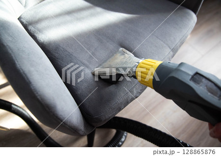 Services for washing and cleaning upholstered furniture with a vacuum cleaner. Cleaning dirty gray chairs in the apartment, industry Services for washing and cleaning upholstered furniture with a vacuum cleaner. Cleaning dirty gray chairs in the apartment, industry 128865876