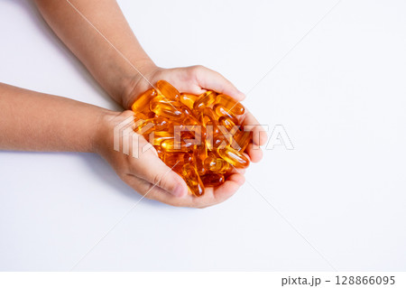 Child hands holding omega 3 fish oil capsules on white background 128866095