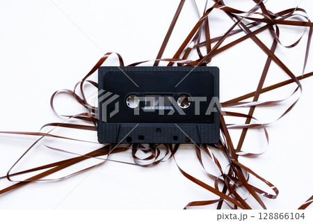Vintage audio cassette with unraveled tape on white background Vintage audio cassette with unraveled tape on white background 128866104