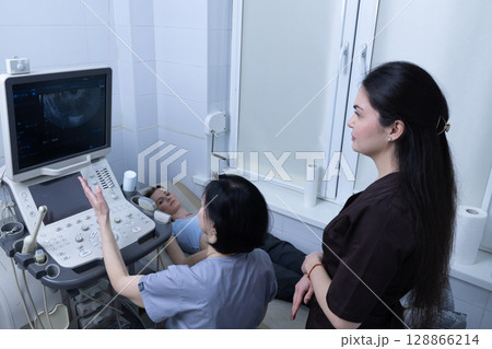 Medical Ultrasound Examination in Progress with Caring Health Professionals and a Patient Undergoing a Diagnostic Procedure in a Modern Healthcare Setting 128866214