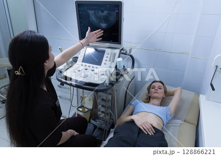 Medical Professional Explaining Ultrasound Results to Patient During Examination in a Clinical Setting, with Equipment and Relaxed Atmosphere Enhancing Care Experience 128866221