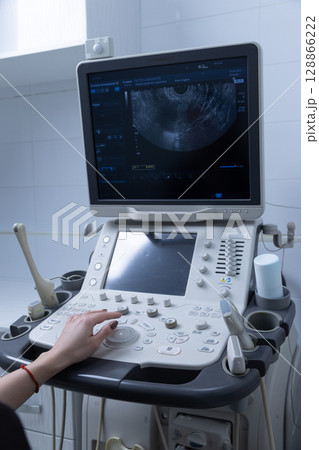 Advanced Ultrasound Machine in a Clinical Setting: Exploring Details on the Screen with a Focused Operator's Hand Adjusting Controls for Optimal Imaging 128866222