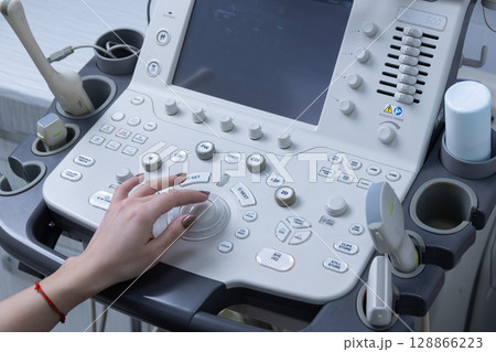 Advanced Ultrasound Machine Controls with a Hand Adjusting Settings - High-Tech Medical Equipment for Imaging and Diagnosis in Healthcare Facilities Advanced Ultrasound Machine Controls with a Hand Adjusting Settings - High-Tech Medical Equipment for Imaging and Diagnosis in Healthcare Facilities 128866223