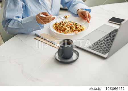 Enjoying a highly productive lunch break with delicious pasta and my laptop nearby in hand Enjoying a highly productive lunch break with delicious pasta and my laptop nearby in hand 128866452