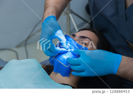Professional Dental Procedure in Progress: Hygienist Applying Rubber Dam on Patient for Improved Oral Health Treatment and Comfort During Procedure Professional Dental Procedure in Progress: Hygienist Applying Rubber Dam on Patient for Improved Oral Health Treatment and Comfort During Procedure 128866453